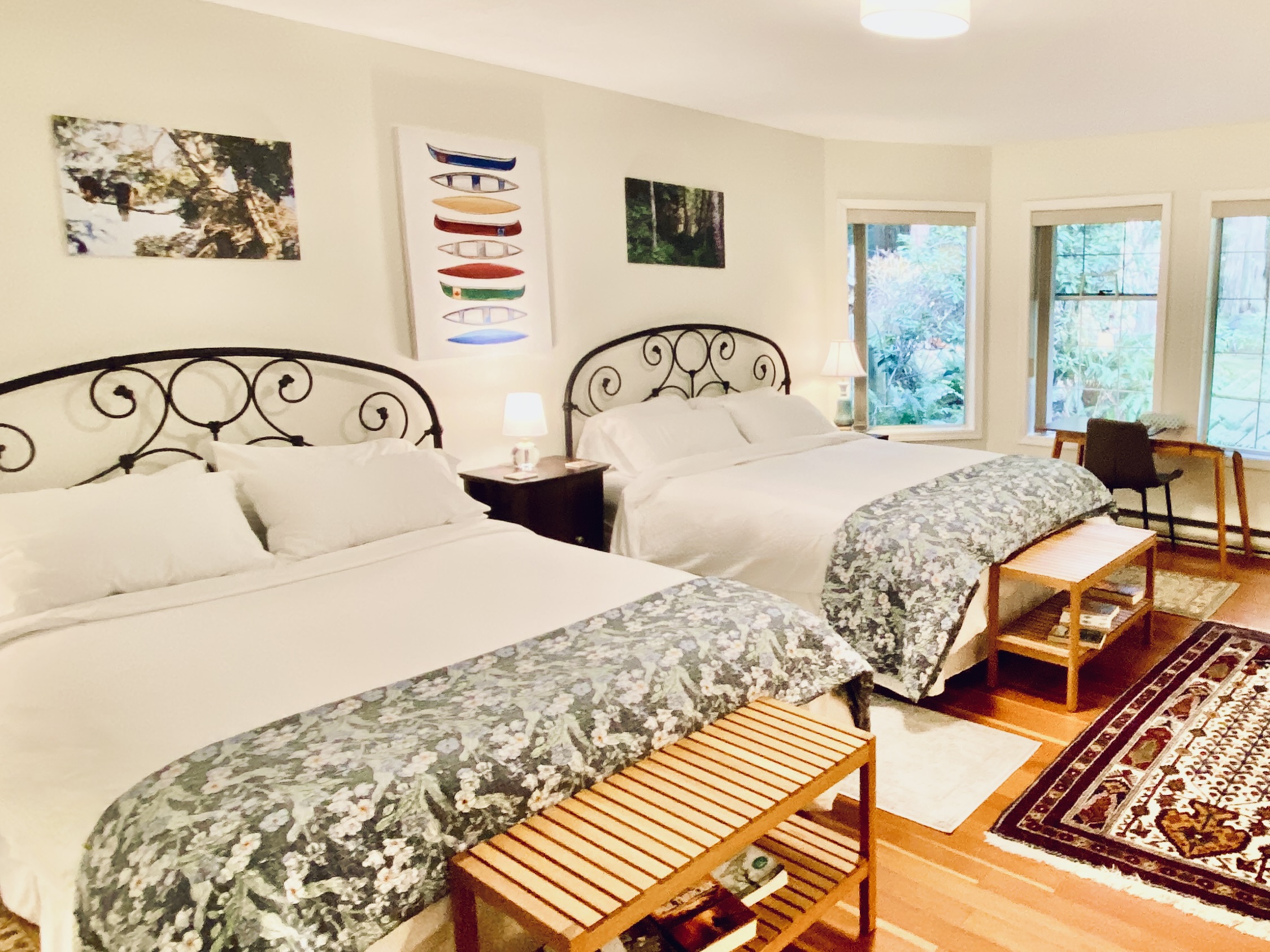 Spacious Rainforest Suite at Ocean Wilderness Inn featuring two queen beds, a dedicated workspace, and artisan canoe wall art.