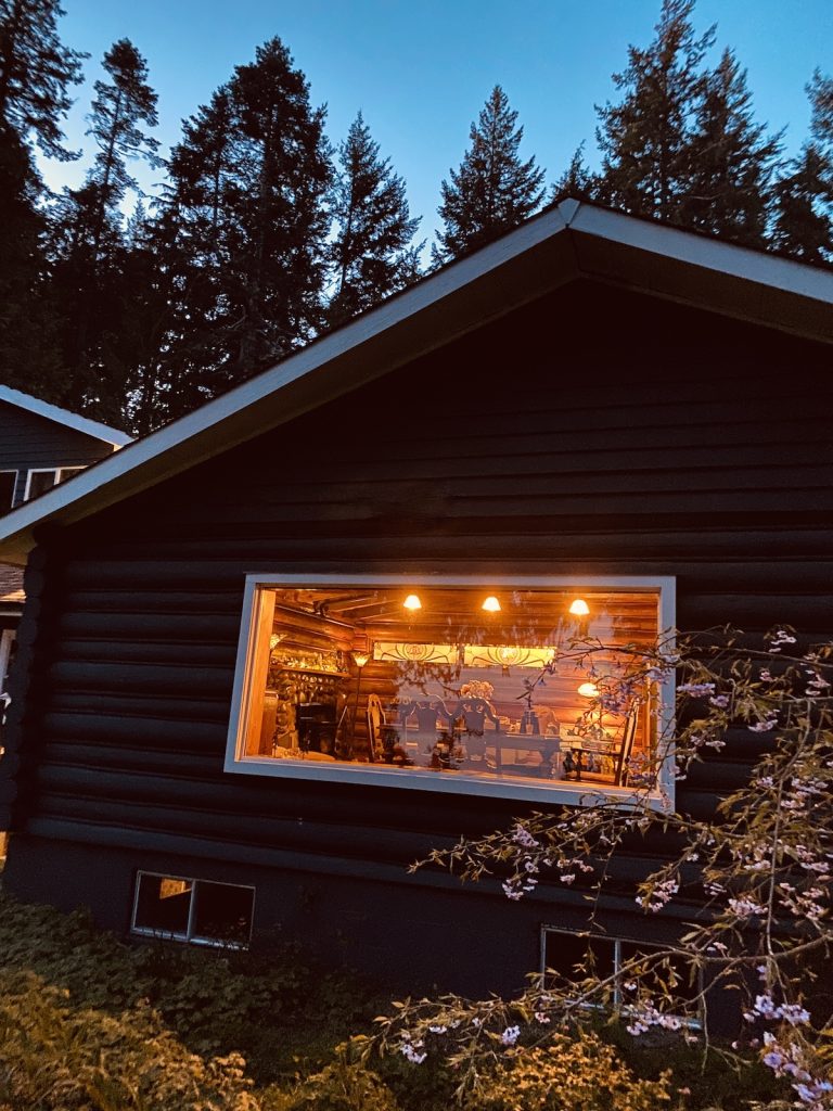 The illuminated cedar lodge at Ocean Wilderness Inn glowing under the night sky in Shirley, BC—a peaceful coastal sanctuary.