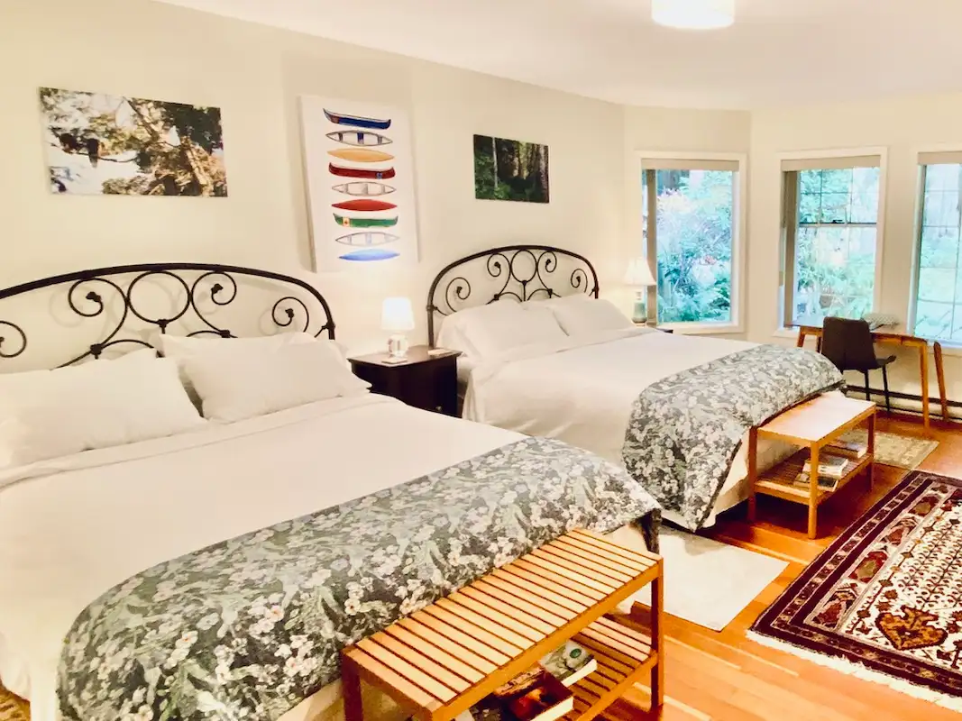 Rainforest Suite at Ocean Wilderness Inn featuring twin queen beds, garden-view patio, and cozy seating area in Shirley, BC.