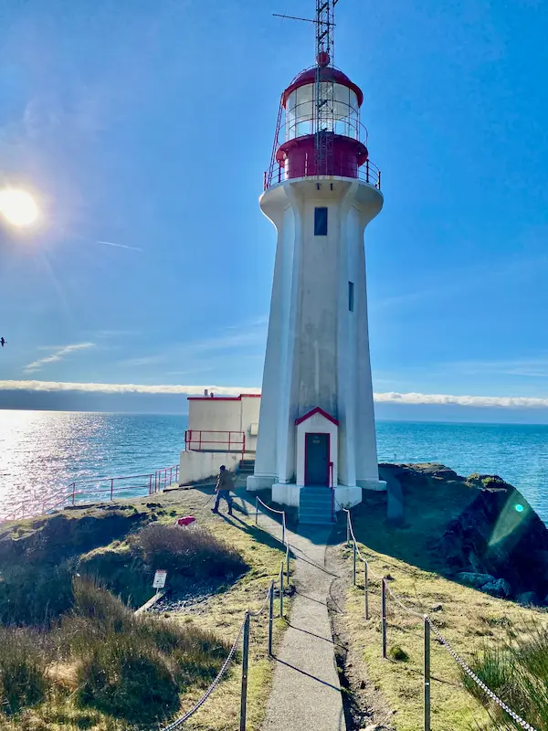 The historic Sheringham Point Lighthouse in Shirley, BC, standing tall against a bright blue sky—a must-see destination just minutes from Ocean Wilderness Inn.