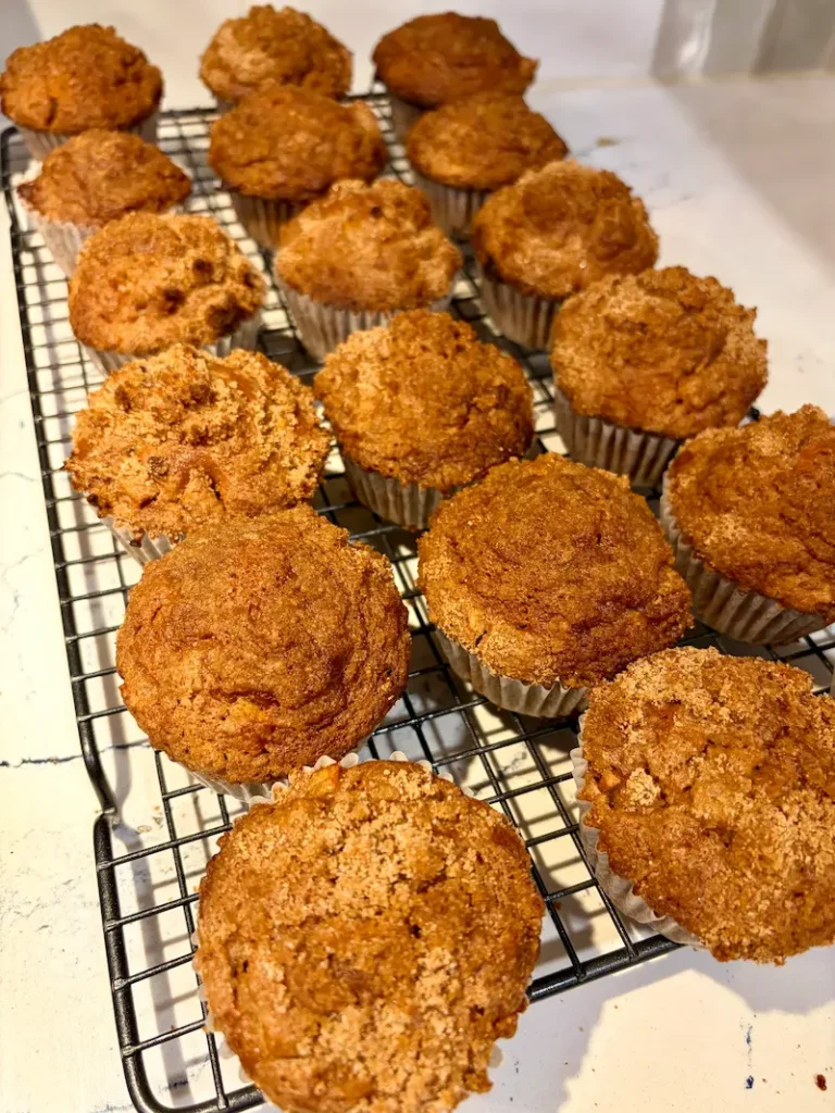 A cooling rack of freshly baked apple-cinnamon crumble muffins cooling on the log dining table at Ocean Wilderness Inn.